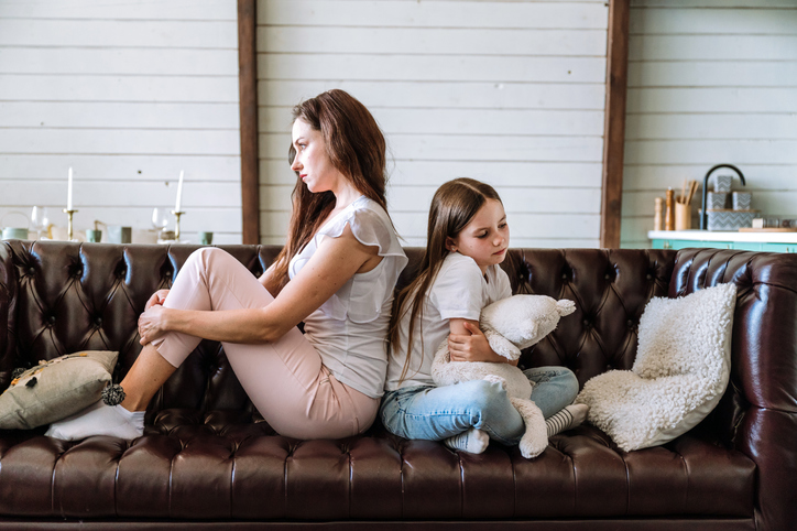 Unhappy mother and daughter sit separately, have family fight or misunderstanding. Upset sad young mom and child avoid talking after quarrel.