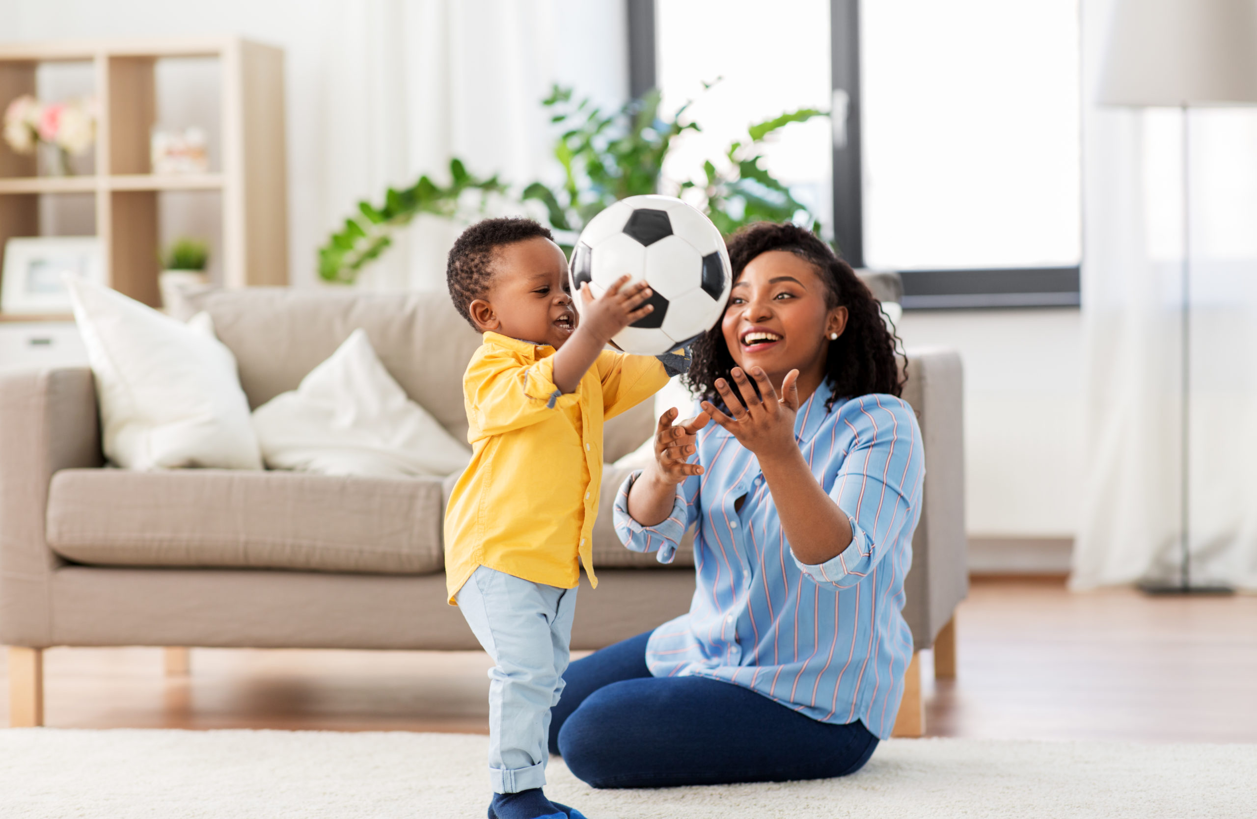mother and baby playing with soccer ball at home