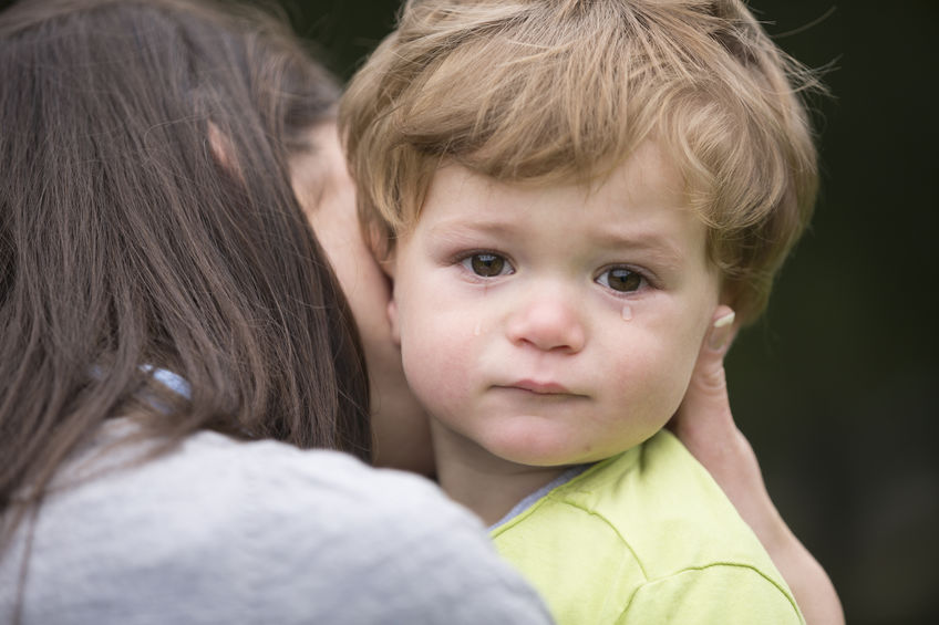 Sad little boy being hugged by his mother.