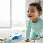 positive routines, Happy mixed race toddler boy crawling in sitting room, blog image, Positive Routines for Toddlers: Eat, Play, and Sleep (Updated for 2026)