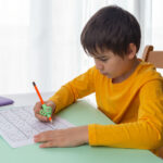 child do homework, boy use ergonomic training pencil holder, correcting pencil grip