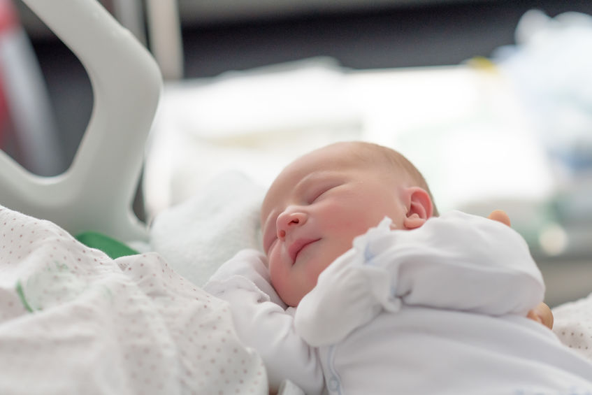 new born infant asleep in the blanket in delivery room