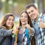 Three happy students with thumbs up