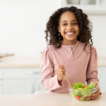 Cheerful african american girl preparing healthy salad