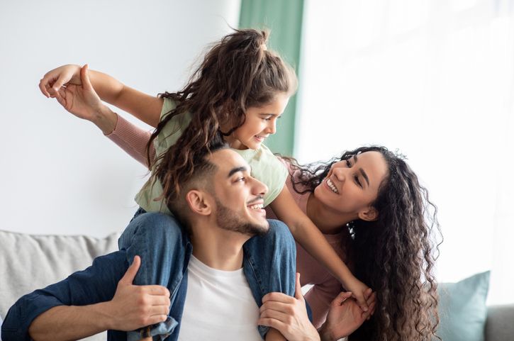 Portraif Of Cheerful Middle Eastern Family Of Three Having Fun Together At Home. Young Arabic Parents Playing With Their Little Daughter In Living Room, Mom, Dad And Child Smiling And Laughing coparenting neurodiversity neuroatypical adhd autism asd, 