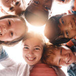 Park, happy and portrait of children in circle for friendship, community and playing together outdoors. Diversity, childhood and low angle of girls and boys for youth, child development and education how to raise independent kids