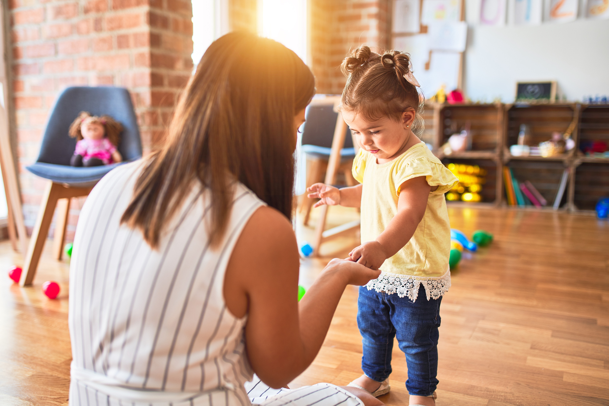 Young beautiful teacher and toddler playing with small building blocks toy at kindergarten, Peace at Home Parenting Solutions